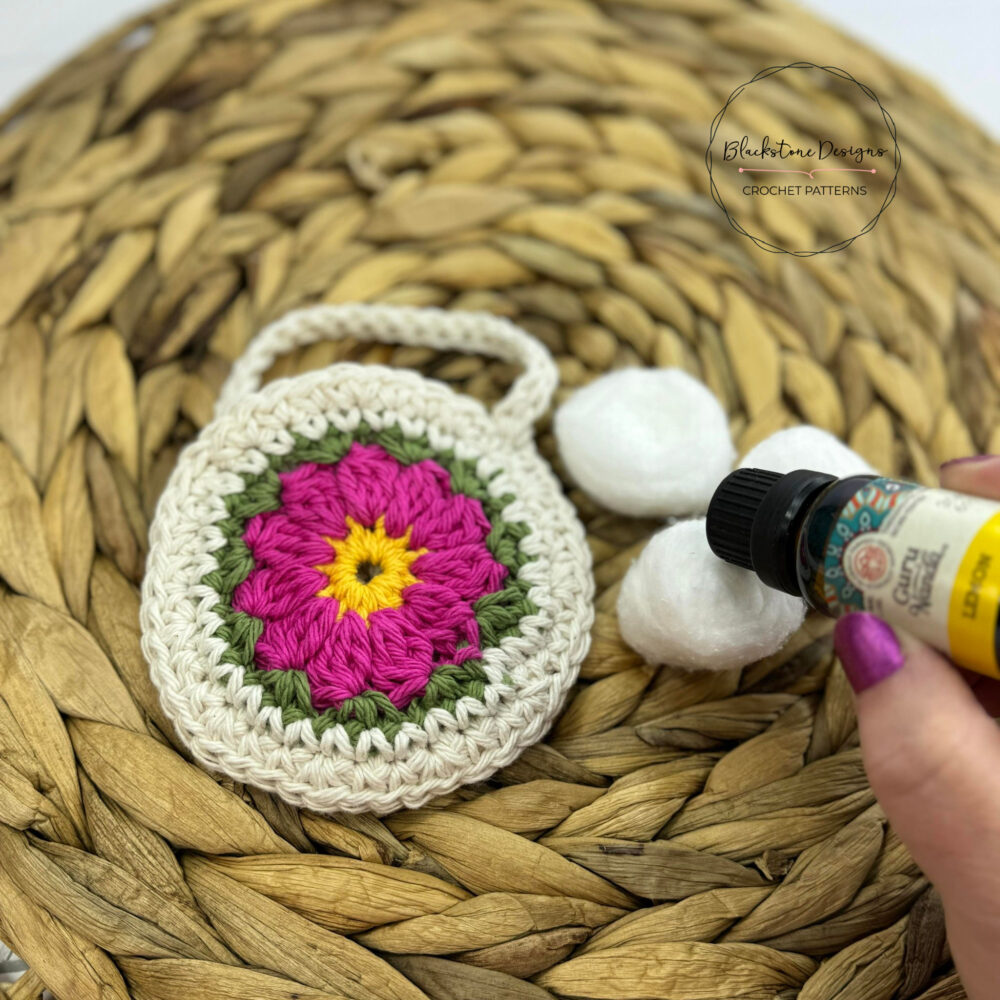 Flower Crochet Air Freshener Pouch Pattern. Round Pouch that has a pink flower with a yellow center.