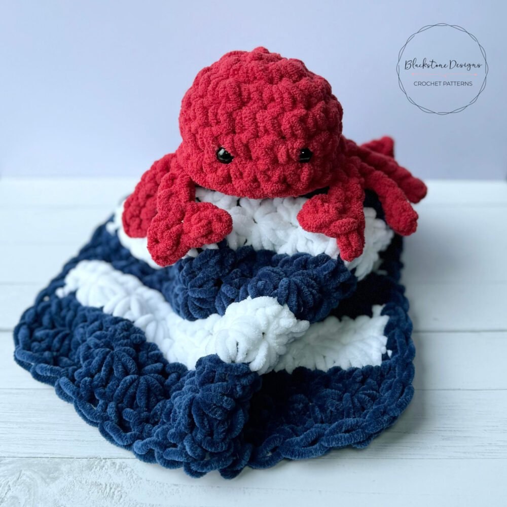 Crochet Feeling Crabby Lovey Blanket Pattern for a crab amigurumi on a blue and white striped chenille blanket
